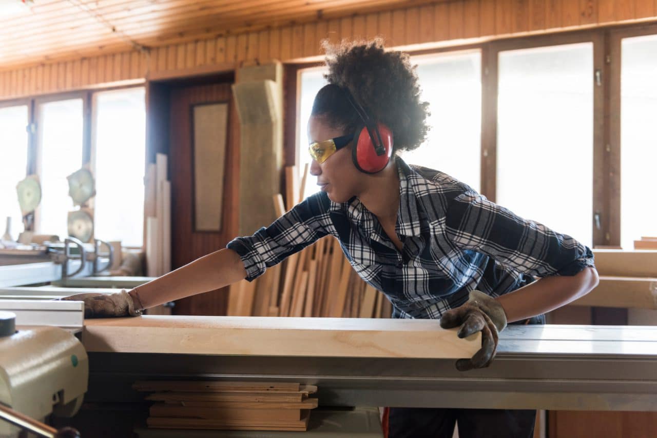 A person wearing hearing and eye protection while woodworking with power tools