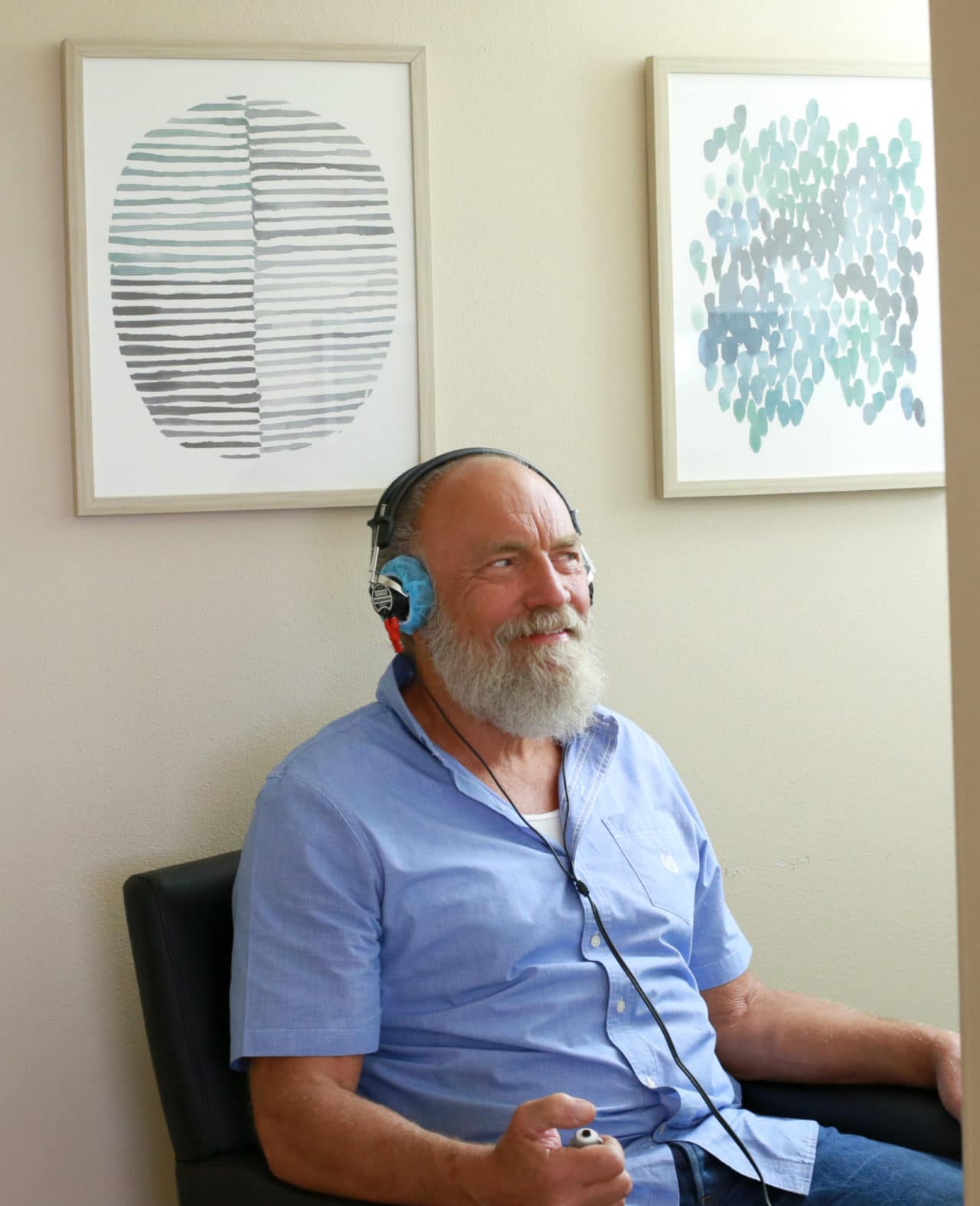 A patient wearing headphones and holding an audiometry button device