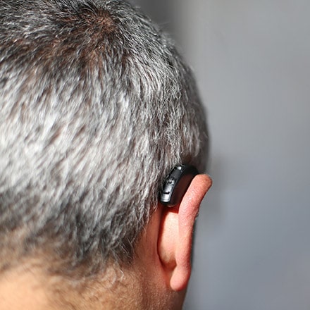 A person wearing a hearing aid from the back