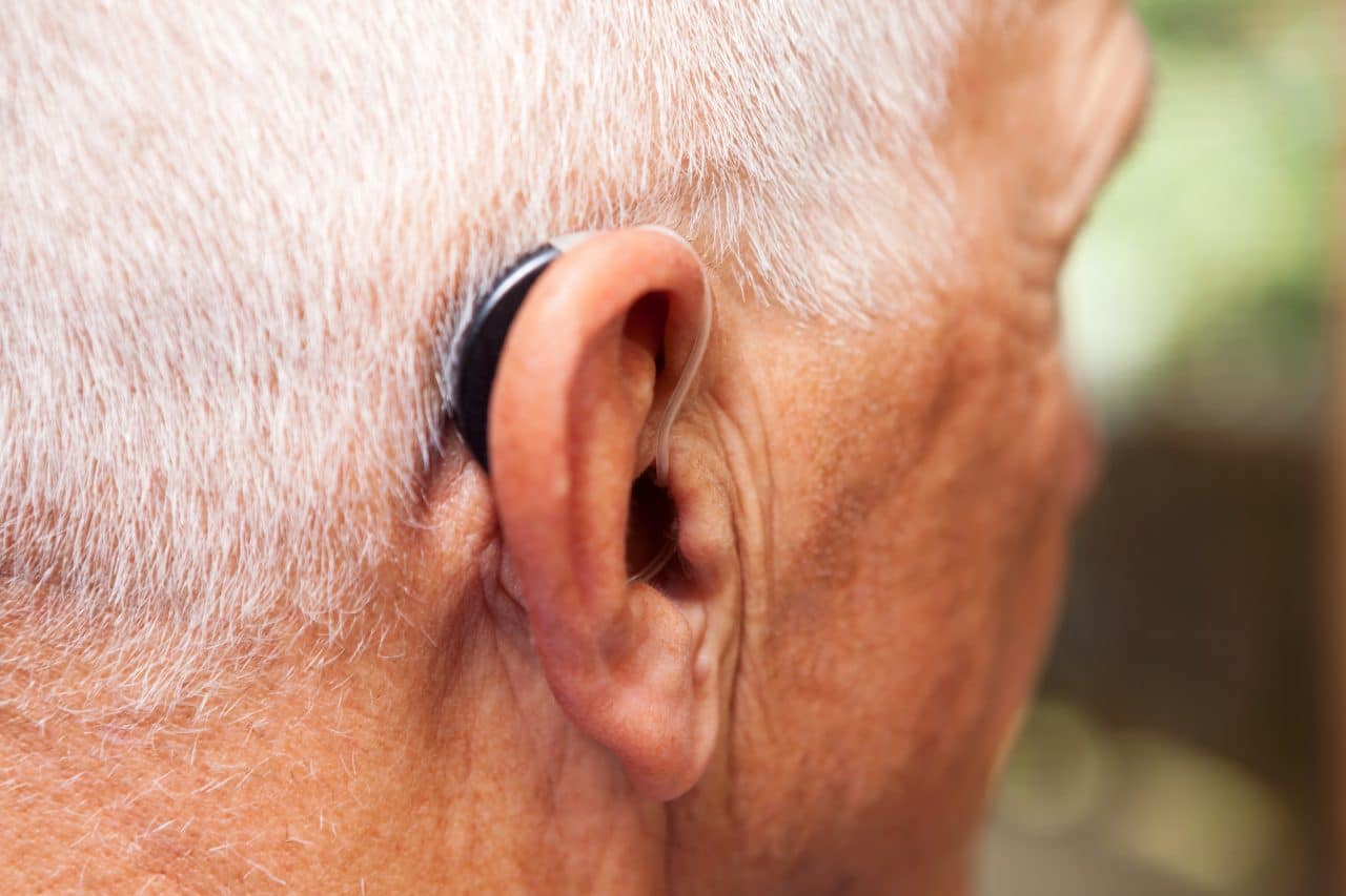 Older man with a very modern, low-profile and discrete hearing aid. 